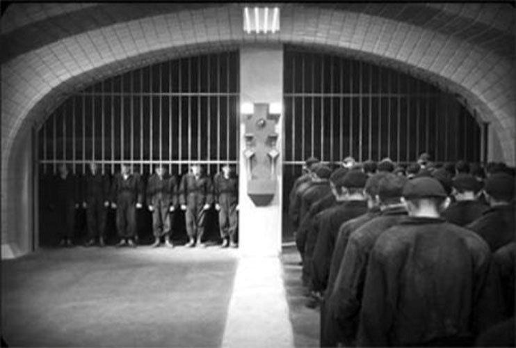 Still from Metropolis - two gates, two queues of uniformed workers