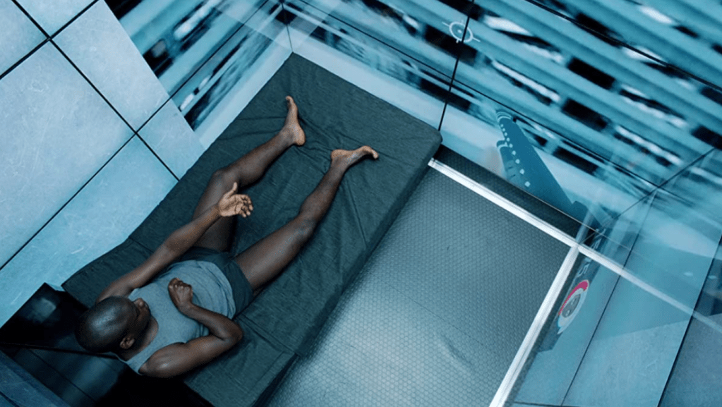 Bing slouches in bed, miming holding a rifle. We can see the barrel of the virtual gun on the screen