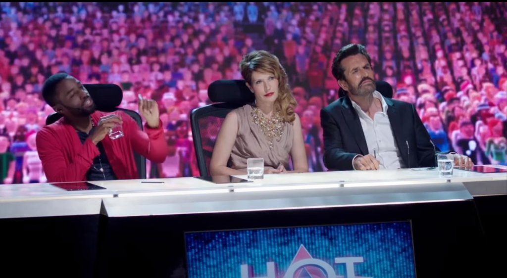 Three judges on a panel, and behind them, a vast audience of virtual doppels